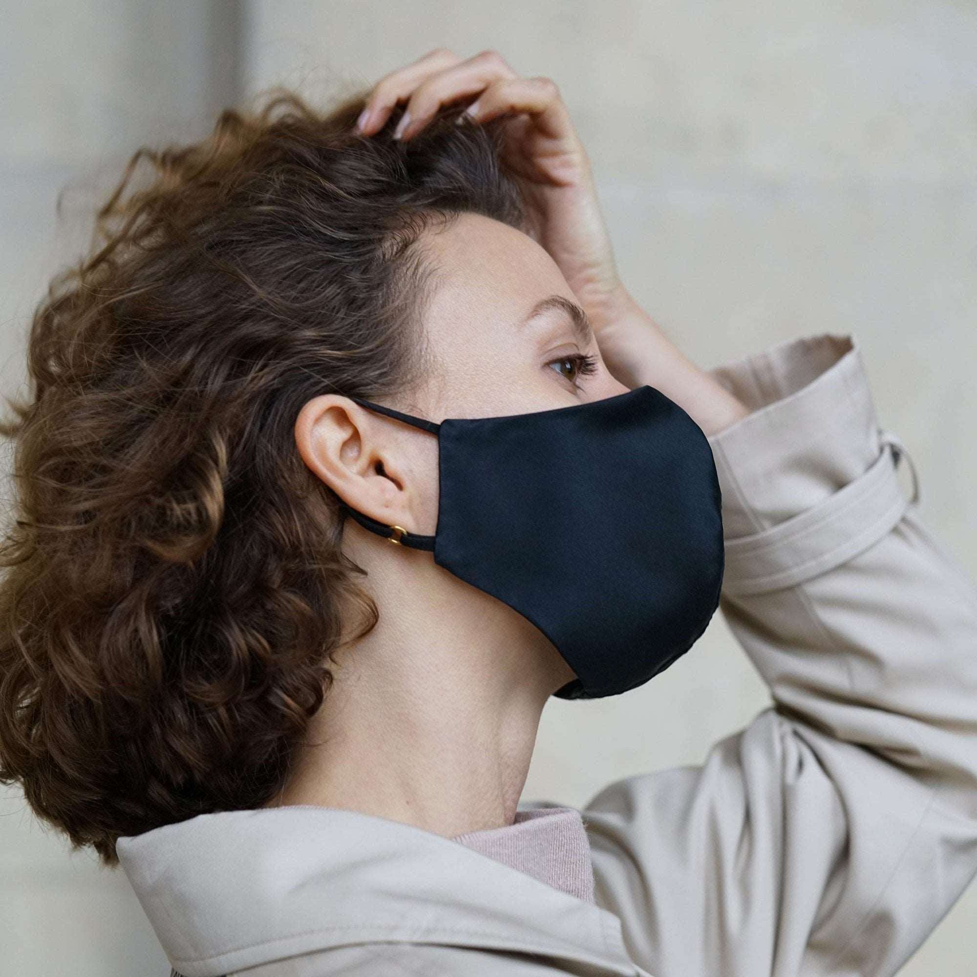 Midnight black silk face mask displayed with a matching black pouch on a white background, by Dariia Day.