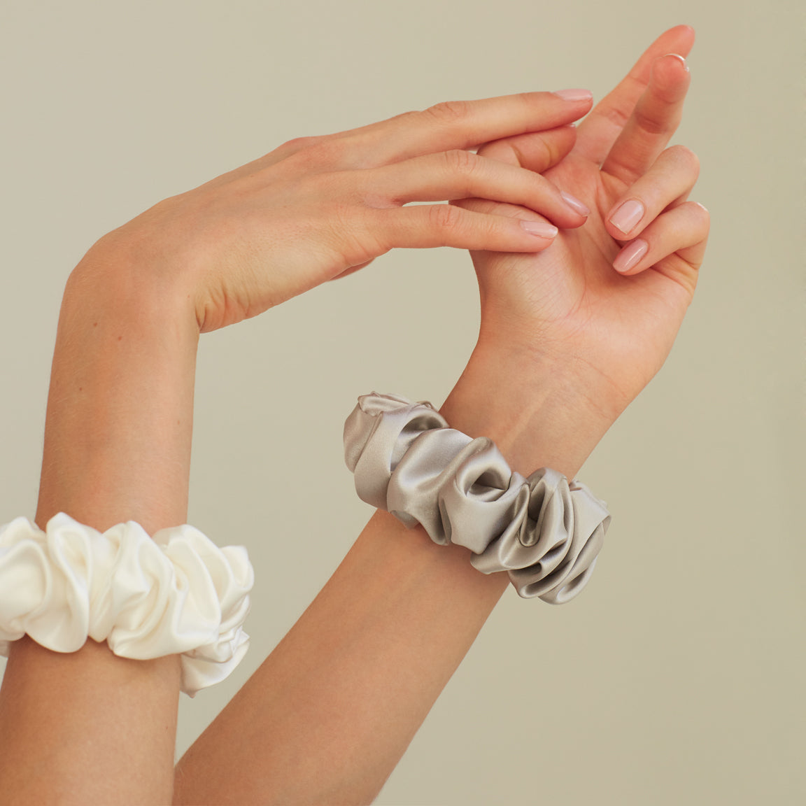 Two luxurious silk scrunchies by Dariia Day, one powder white and one silver grey, perfect for stylish hair accessories.