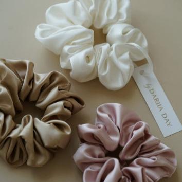 Close-up of 3 silk scrunchies in beige, pink, and white by Dariia Day, highlighting the smooth texture of the silk.