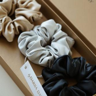 Set of 4 silk scrunchies in beige, white, grey, and black, displayed in a luxury box by Dariia Day.