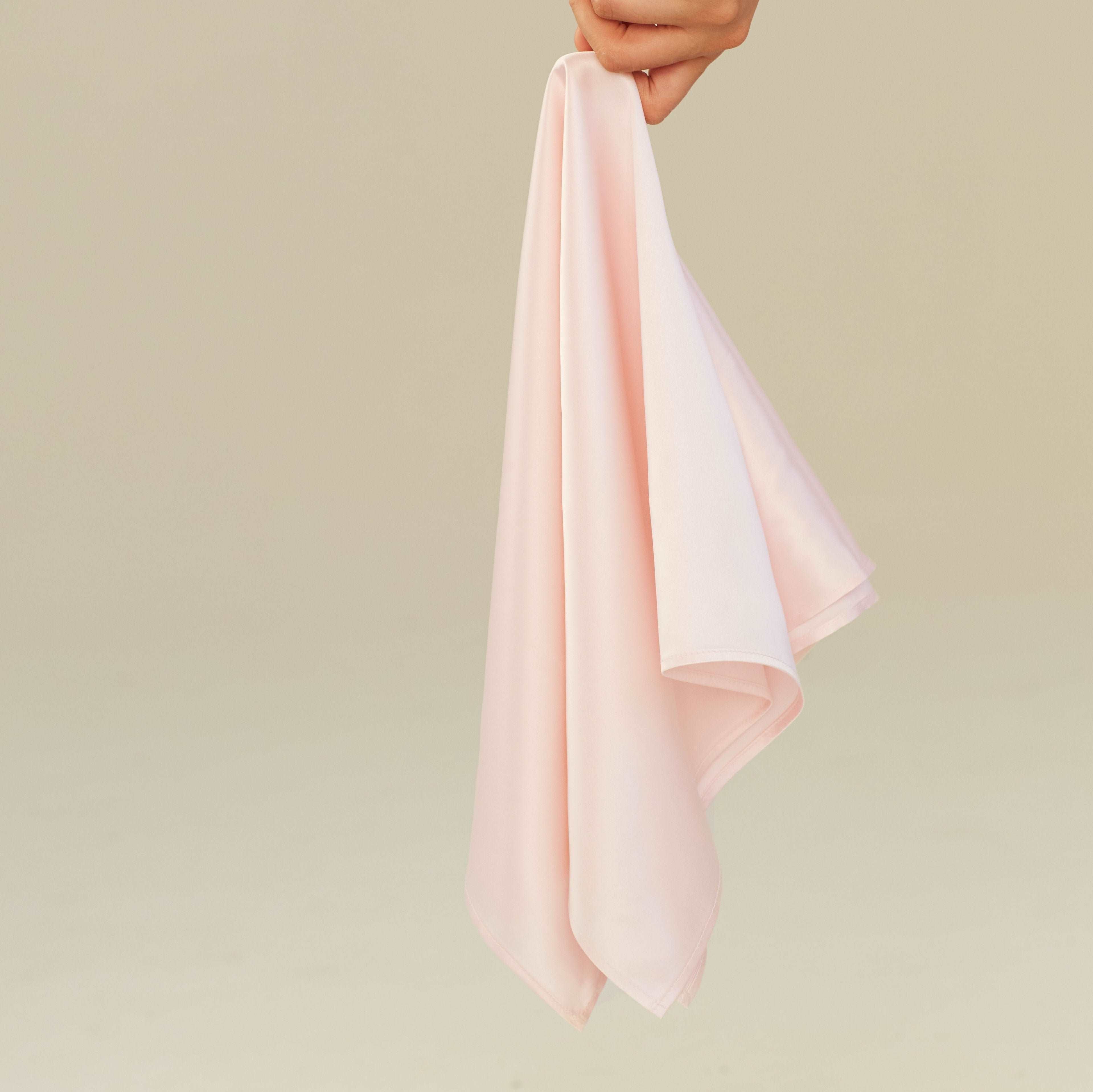 Pink Blush pink silk scarf square by Dariia Day, gently held in hand, showcasing its smooth, delicate fabric.