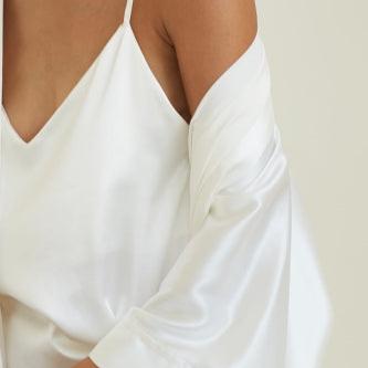 Detail shot of powder white silk top by Dariia Day with draped silk sleeve.