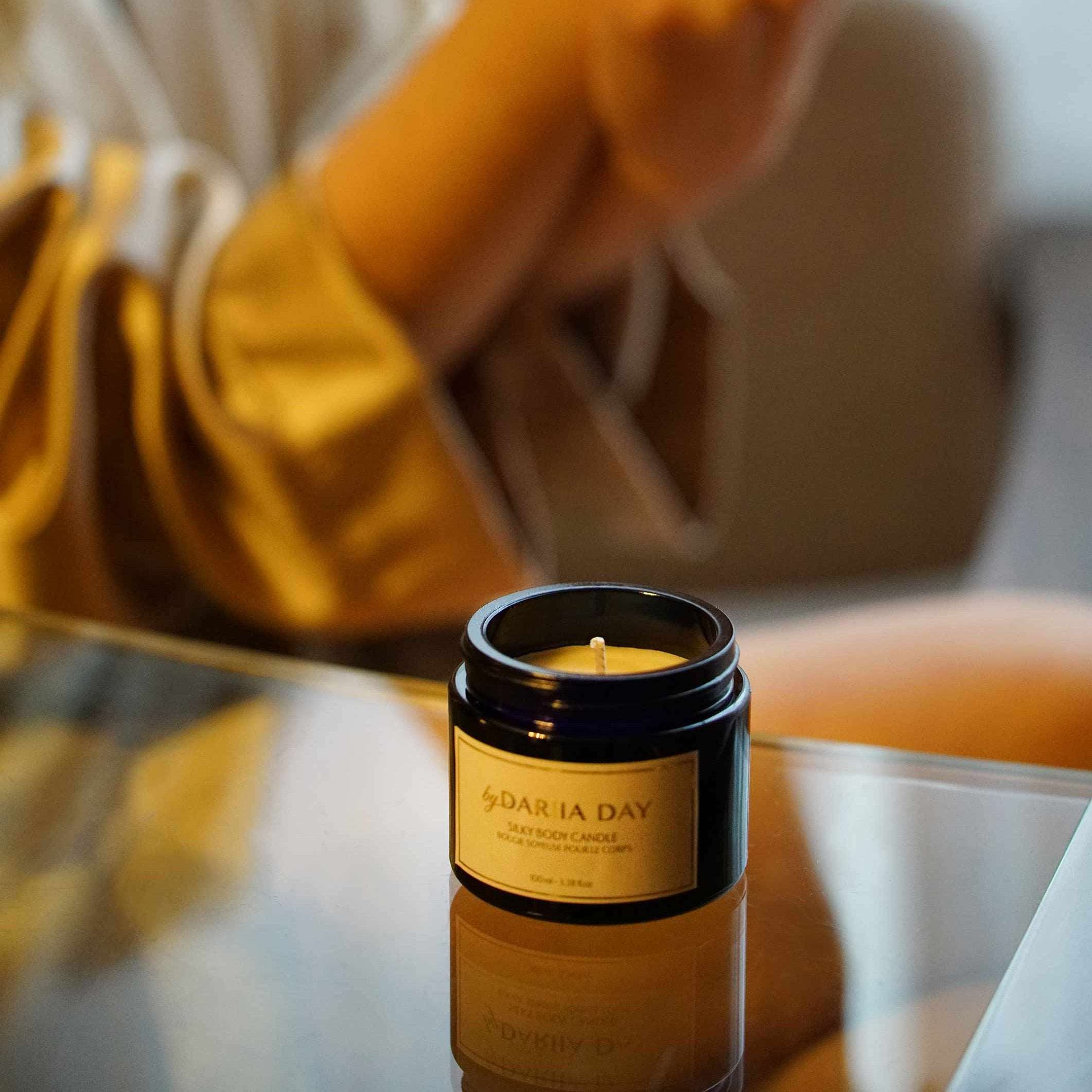 Close-up of a Silky Body Candle by Dariia Day held in hand, showcasing its luxurious black jar and label