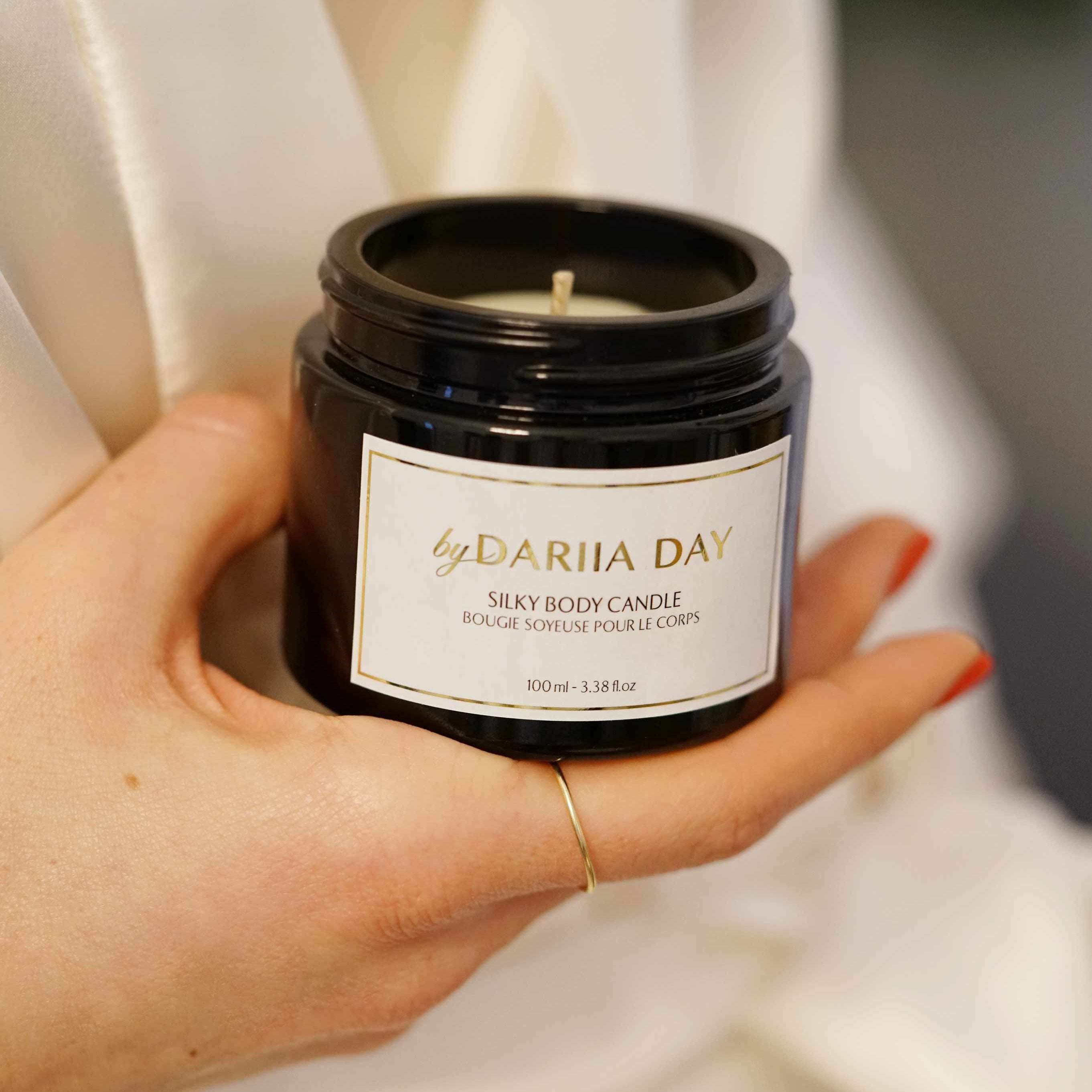 Close-up of a Silky Body Candle by Dariia Day held in hand, showcasing its luxurious black jar and label.