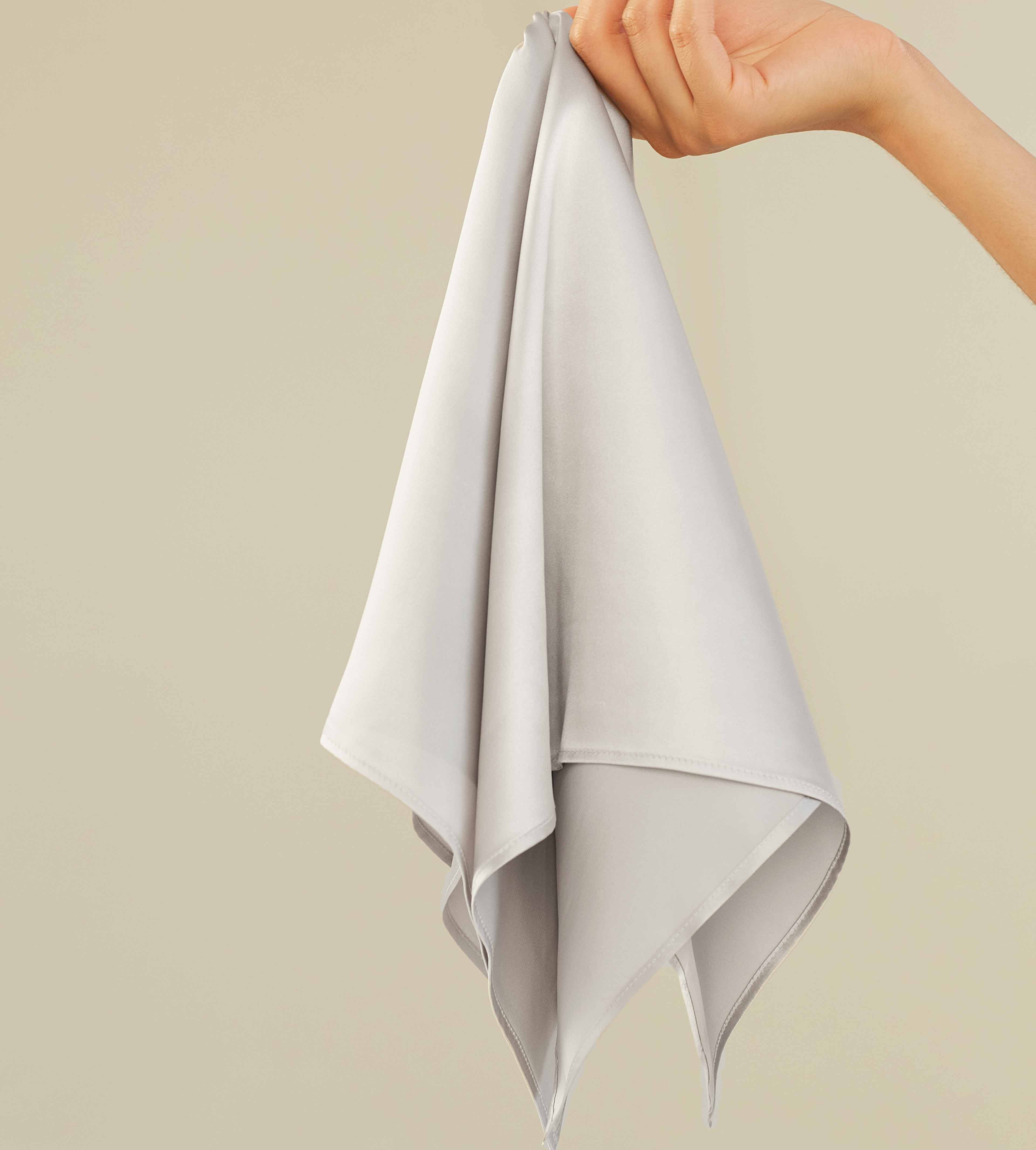 Silver A hand holding a silver grey silk scarf by Dariia Day, displaying the soft and premium fabric